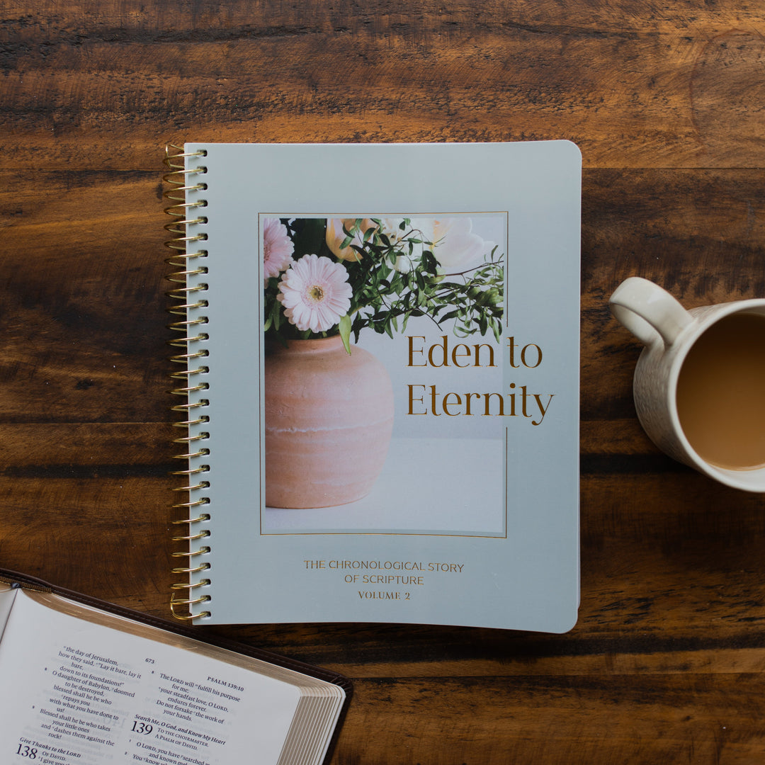 Eden to Eternity Spiral cover on a wooden table next to a coffee cup and an open bible