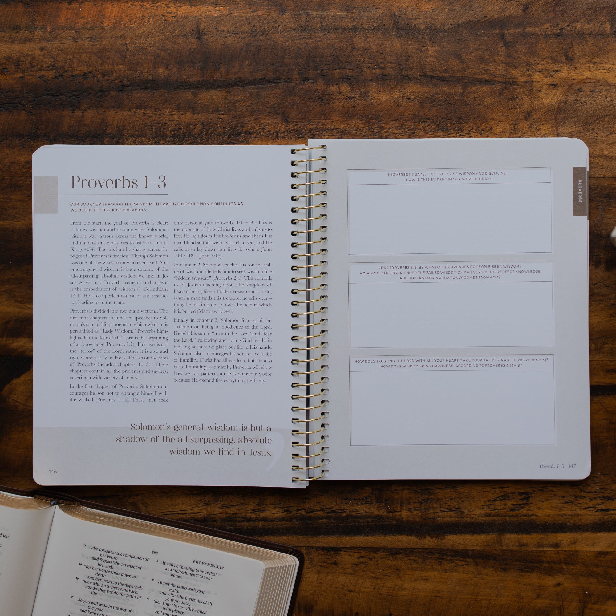 Eden to Eternity Spiral opened to the Proverbs 1 reading and questions page on a wooden table next to an open bible