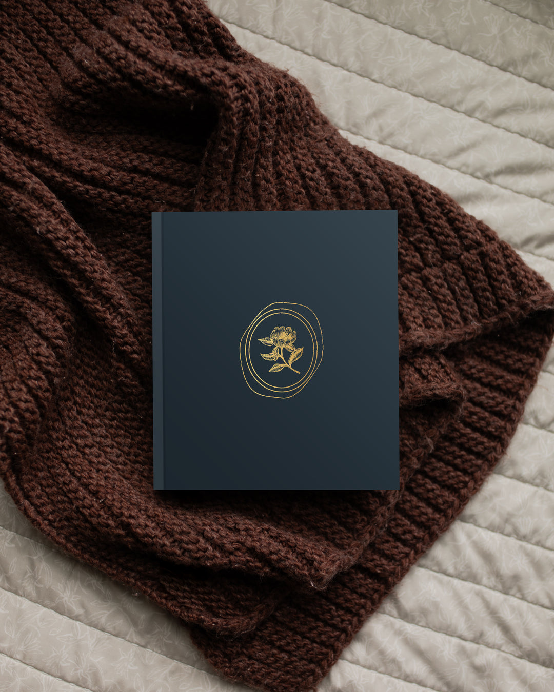 Dark blue card with gold emblem on a brown knitted fabric