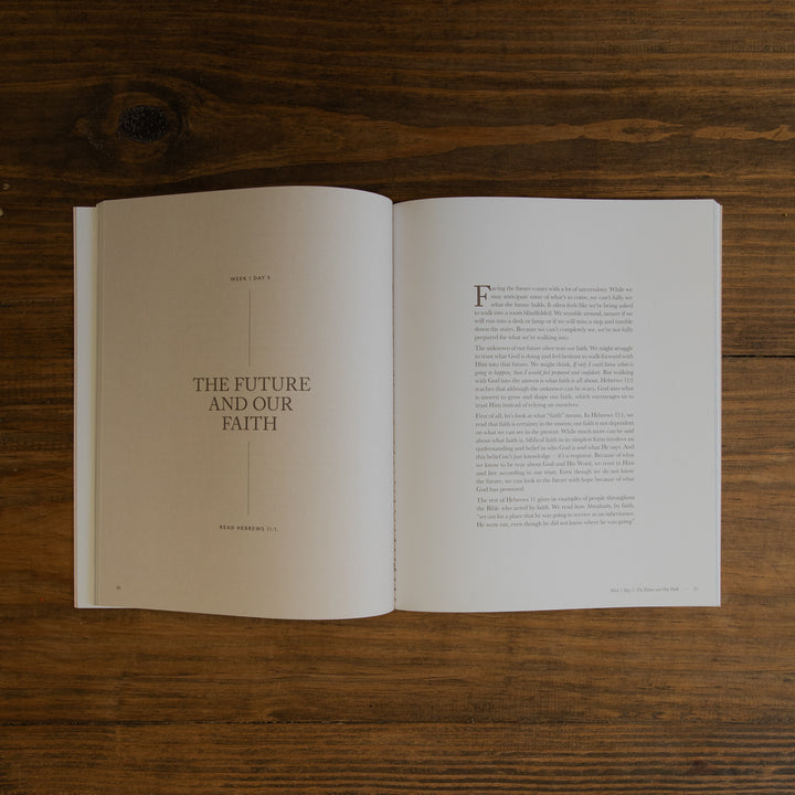 An open book displaying two printed pages with text, laid flat on a dark brown wooden surface. The left page has the title 'THE FUTURE AND OUR FAITH' in a clean serif font, and the right page contains paragraphs of text with a large decorative initial 'F'.