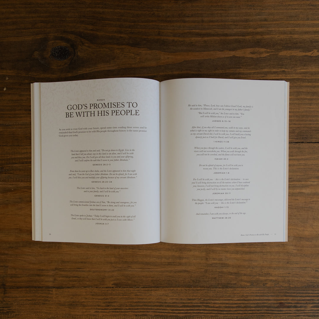 An open book laid flat on a dark wood surface, showing two spread pages with printed text. The left page has the title 'God's Promises to Be With His People' in large serif font, and the right page contains smaller text blocks below.