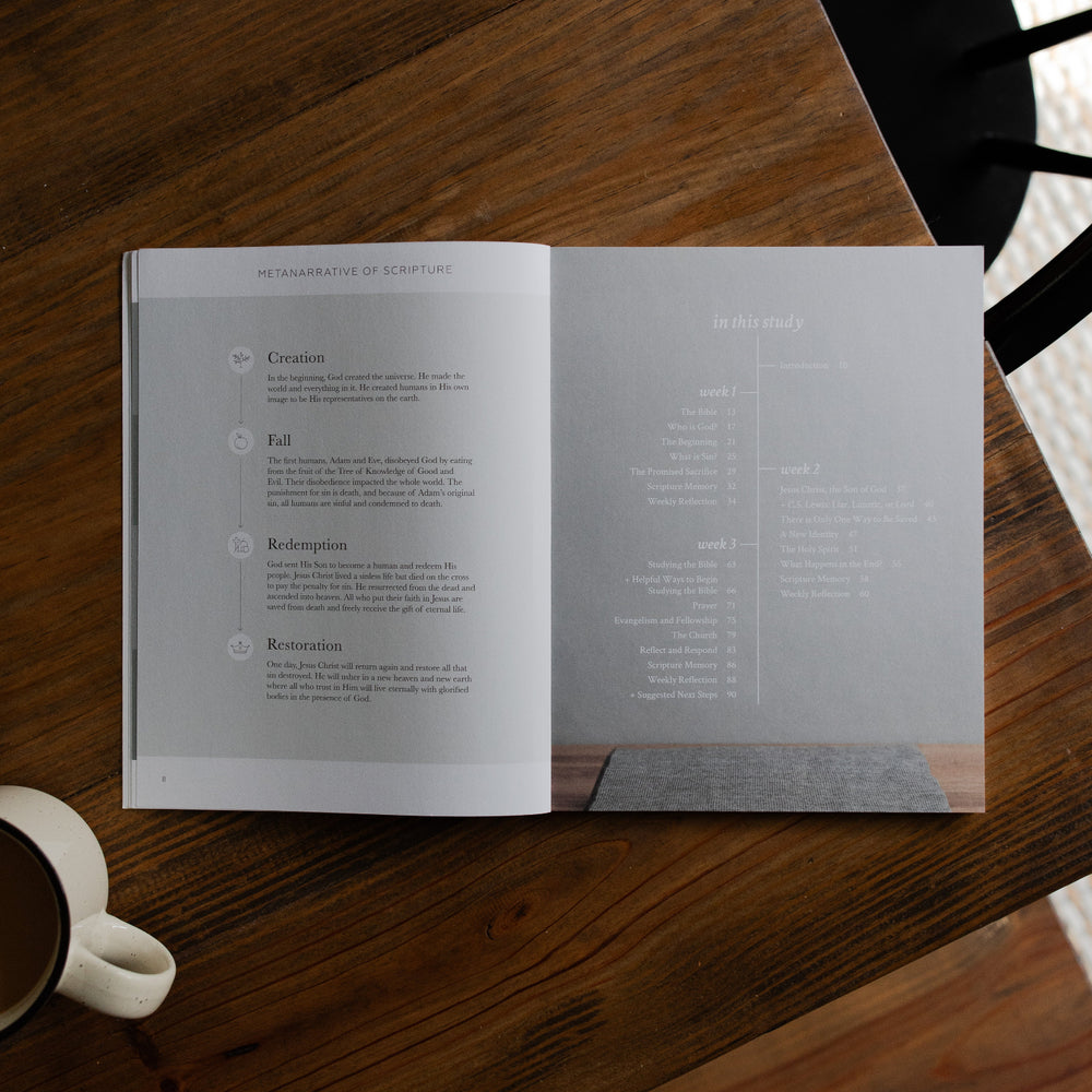 Faith Foundations Mens study opened to the table of contents page on a brown wooden table next to a white coffee cup