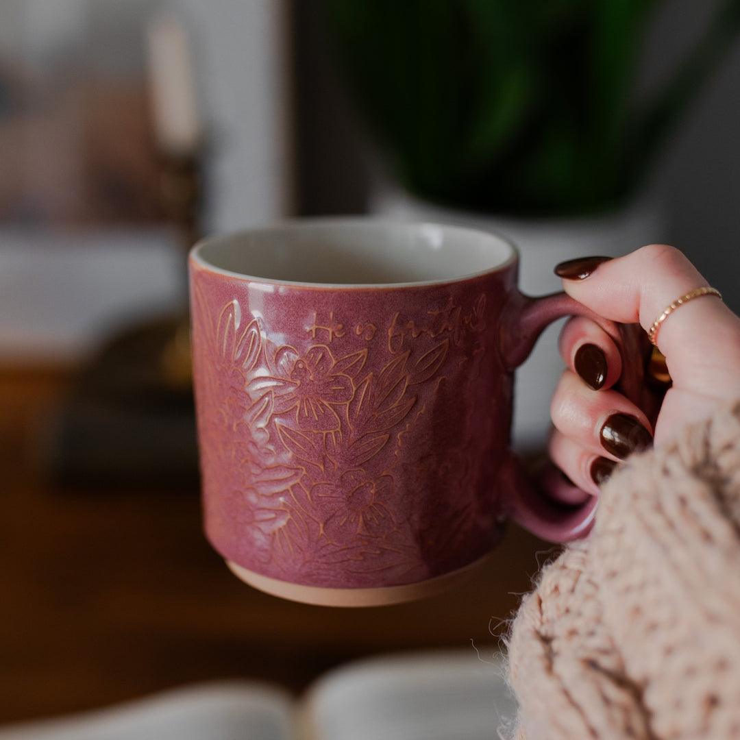 woman holding christian mug that says he is faithful 