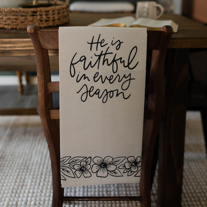 He is Faithful in Every Season Christian Tea Towel hanging on chair