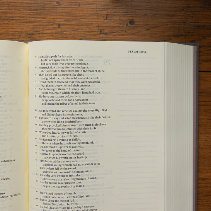 A Bible verse bible page showing Psalm 78:72 printed in black text on white paper, photographed from above on a dark wood surface.
