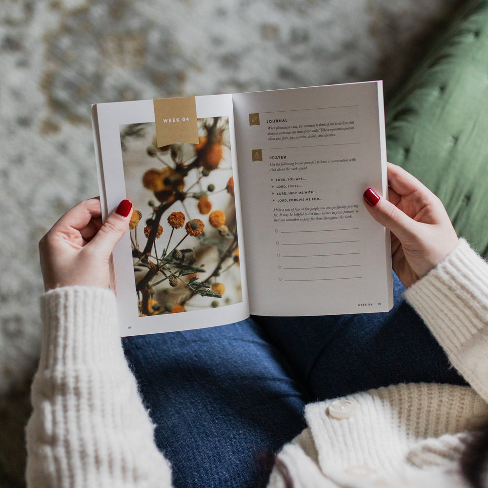 Person holding an open book with a floral illustration on a textured surface