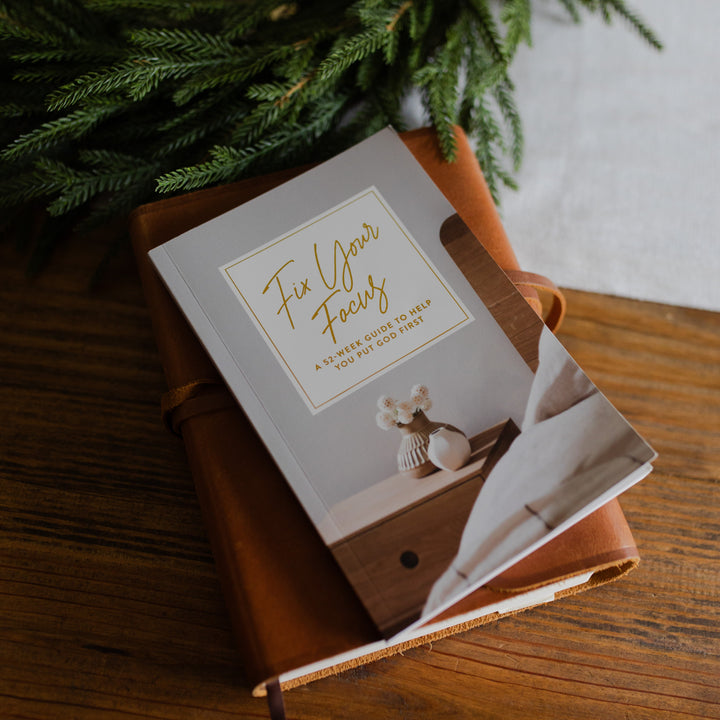 Weekly Devotional on a wooden surface with greenery in the background