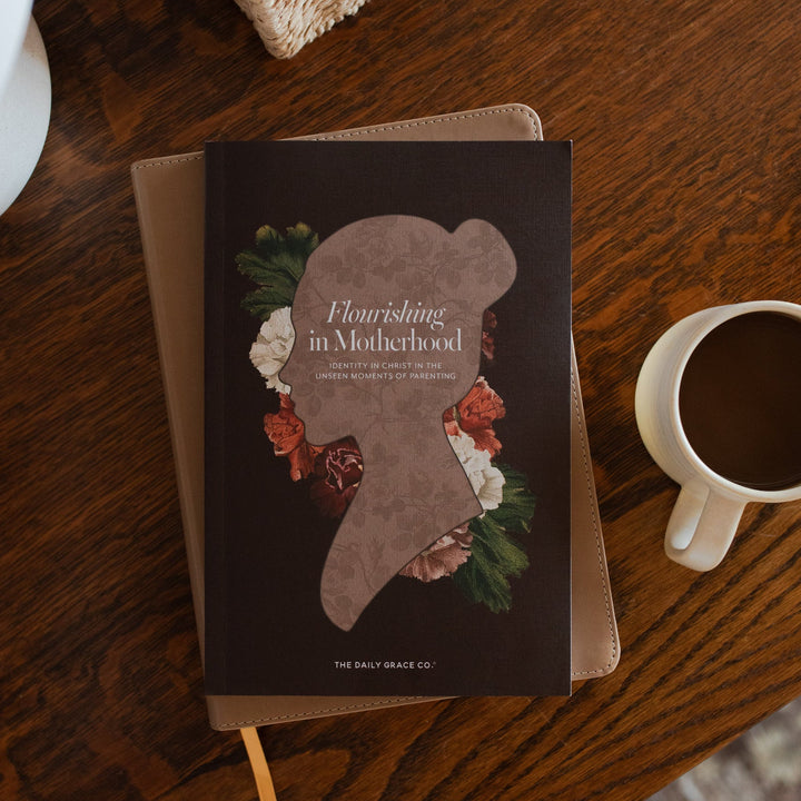 Flourishing in Motherhood Book cover on a closed bible on a wooden table near a coffee cup