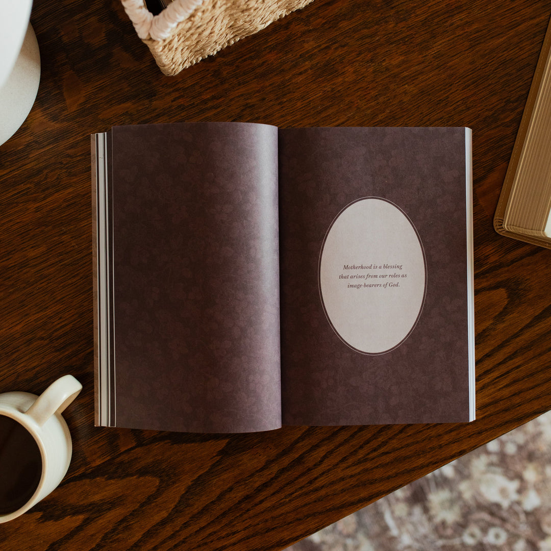 Flourishing in Motherhood Book opened to the small devotional page on a wooden table near a coffee cup