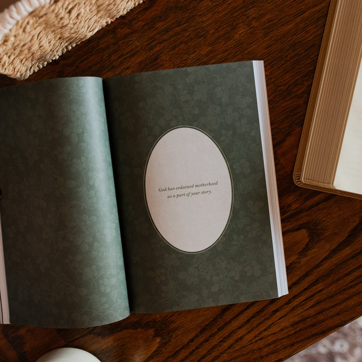 Flourishing in Motherhood Book opened to a devotional page on a wooden table 