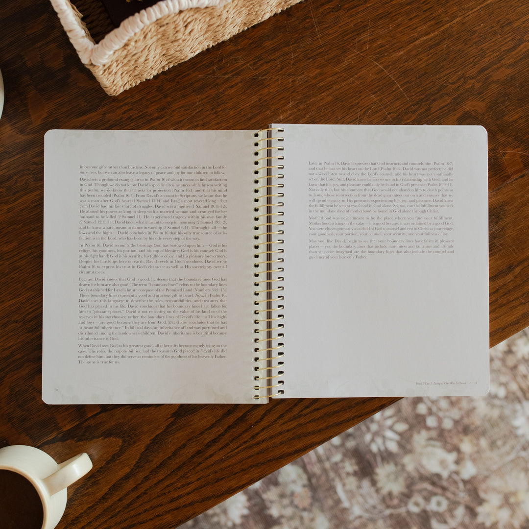 Flourishing in Motherhood spiral study opened to the end of a reading page on a wooden table near a coffee cup