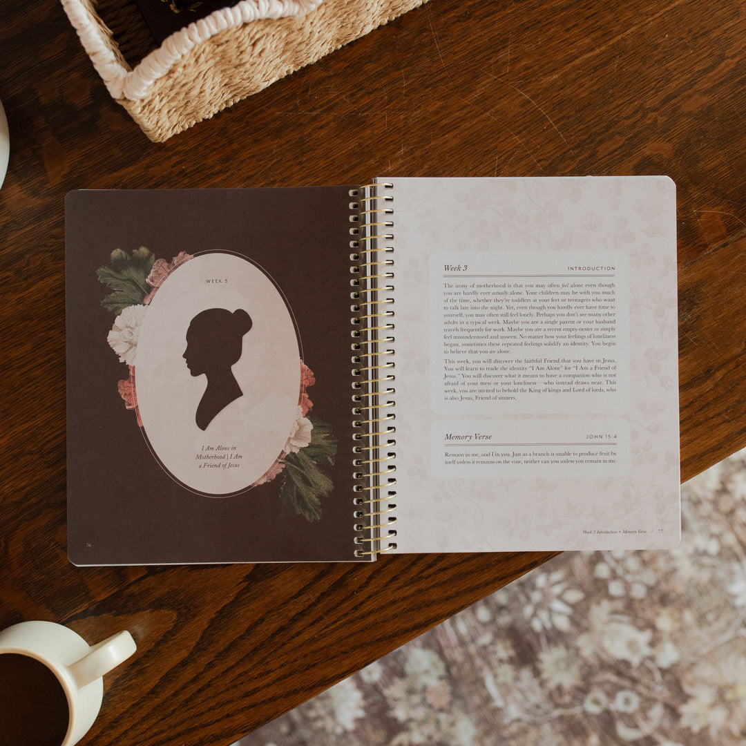 Flourishing in Motherhood spiral study opened to the week 3 introduction page on a wooden table near a coffee cup