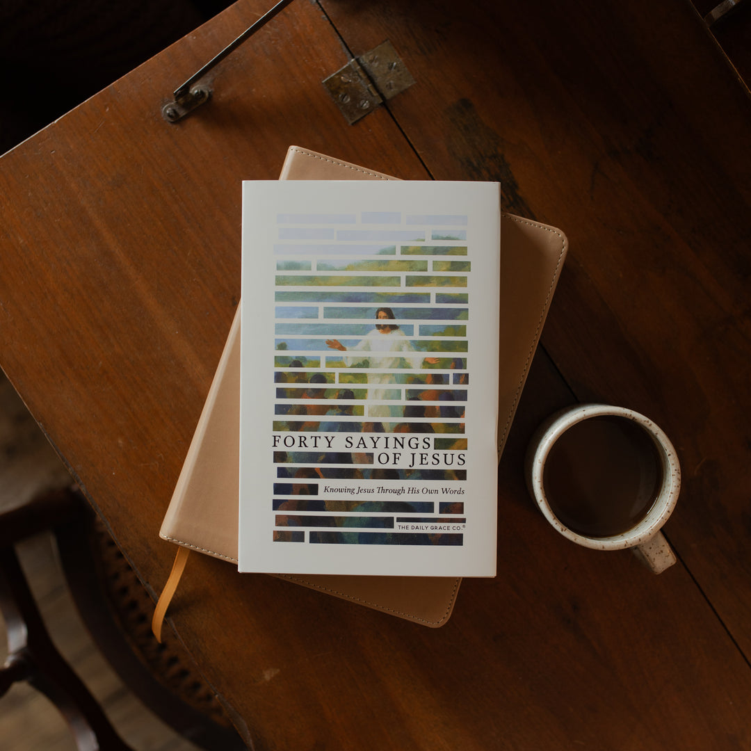 Forty Sayings of Jesus hardcover cover on a closed bible near a coffee cup on a wooden table