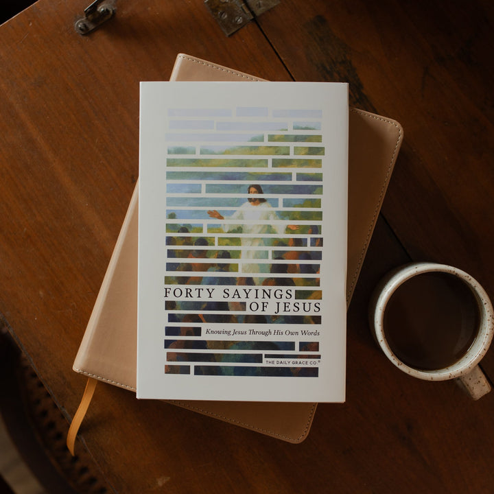 Forty Sayings of Jesus hardcover cover on a closed bible near a coffee cup on a wooden table