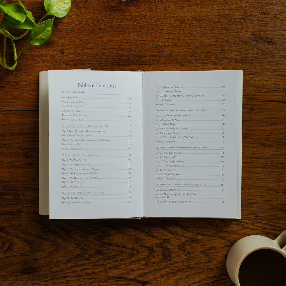 Forty Sayings of Jesus hardcover opened to the Table of Contents page near a coffee cup on a wooden table