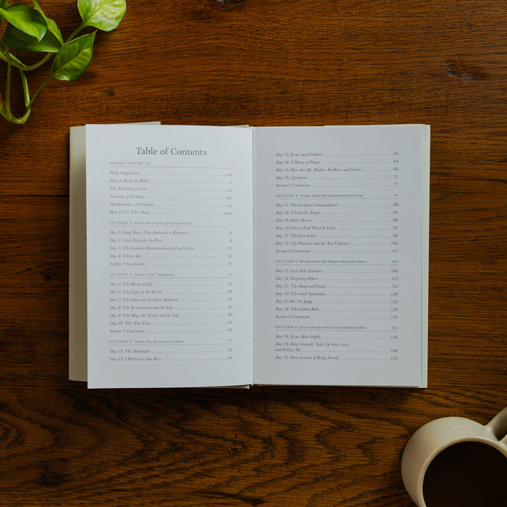 Forty Sayings of Jesus hardcover opened to the Table of Contents page near a coffee cup on a wooden table