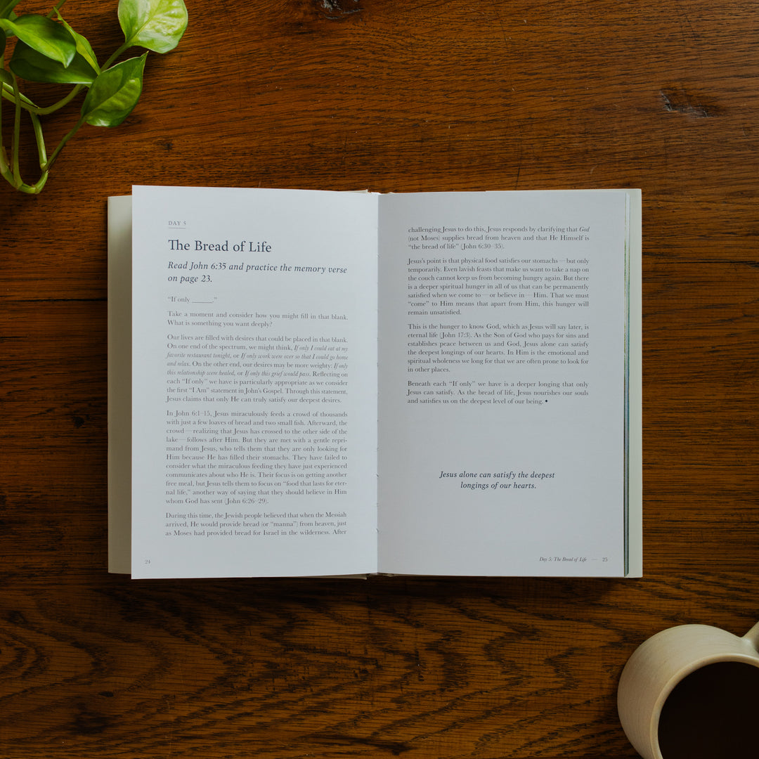 Forty Sayings of Jesus hardcover opened to the Bread of Life page near a coffee cup on a wooden table