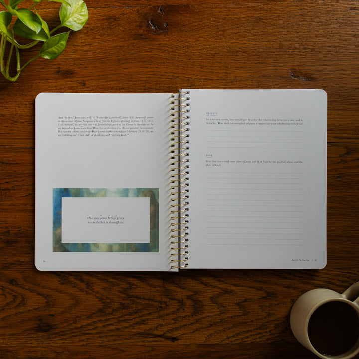 Forty Sayings of Jesus spiral opened to the reflections and applications page near a coffee cup on a wooden table