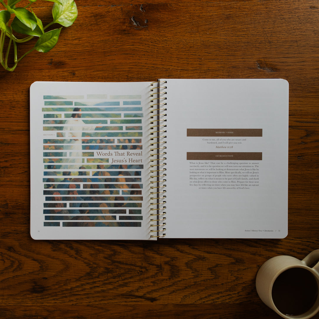 Forty Sayings of Jesus spiral opened to the Words that reveal Jesus's Heart page near a coffee cup on a wooden table