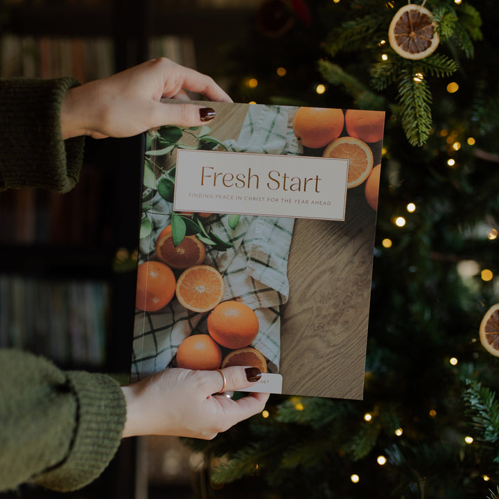 A woman holding the Fresh Start Bible study near a Christmas tree