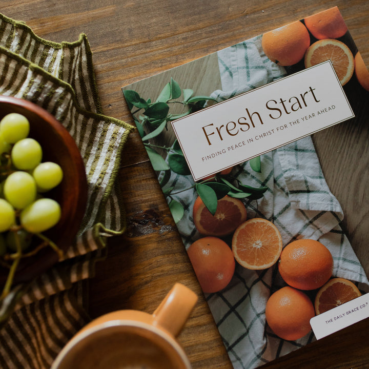 Fresh Start Bible cover on a wooden table next a green striped towel and a bowl of grapes