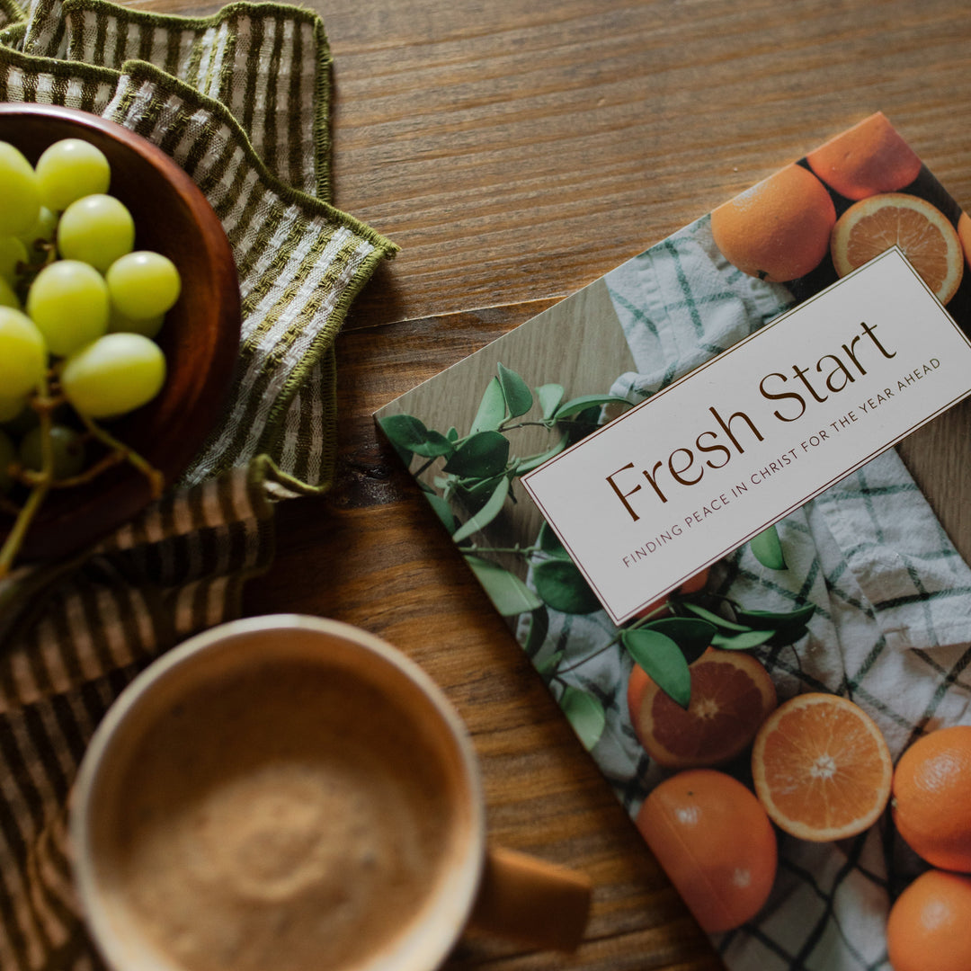 Fresh Start Bible cover close up on a wooden table next a green striped towel and a bowl of grapes