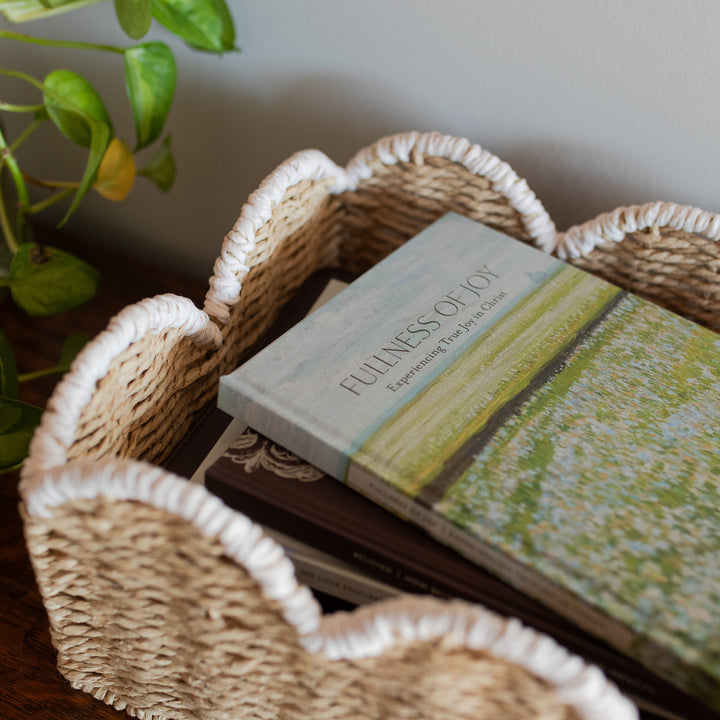 The Fullness of Joy cover on a stack of other daily grace books in a woven basket