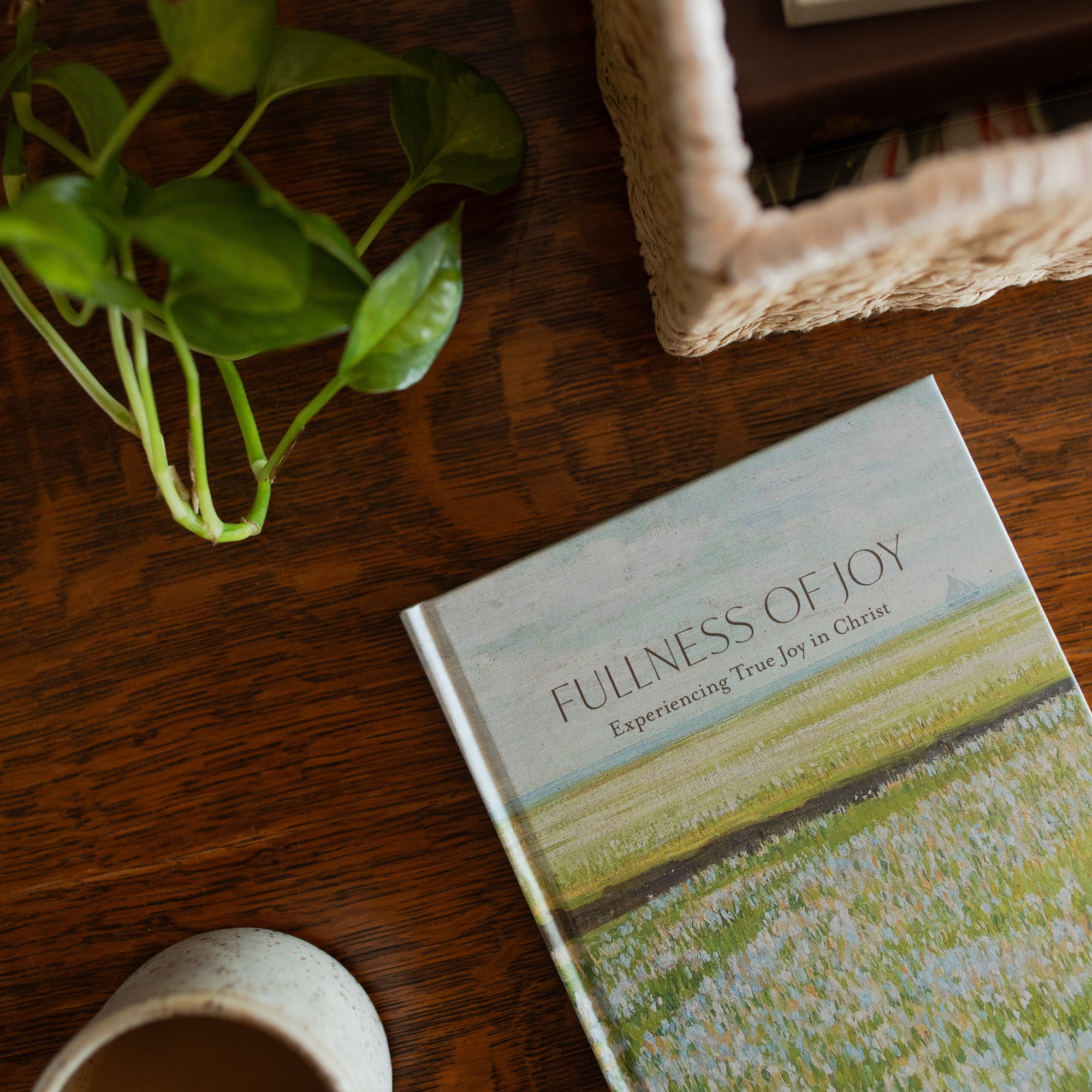 The Fullness of Joy cover on a wooden table near a woven basket and a coffee cup