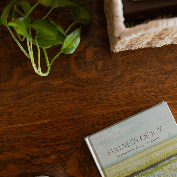 The Fullness of Joy cover on a wooden table near a woven basket and some greenery