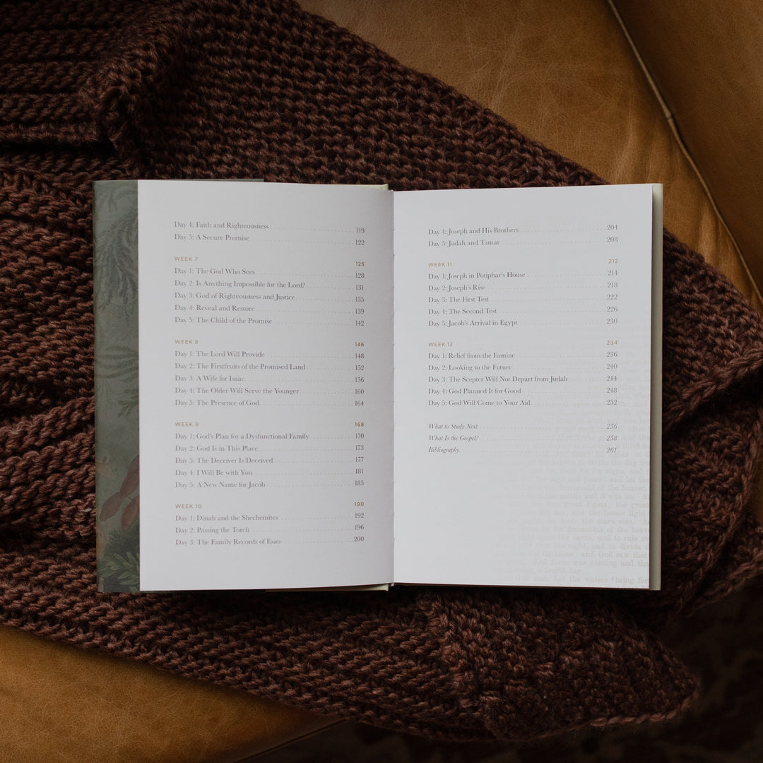 Genesis Hardcover study opened to the end of the table of contents page on a woven blanket on a leather couch