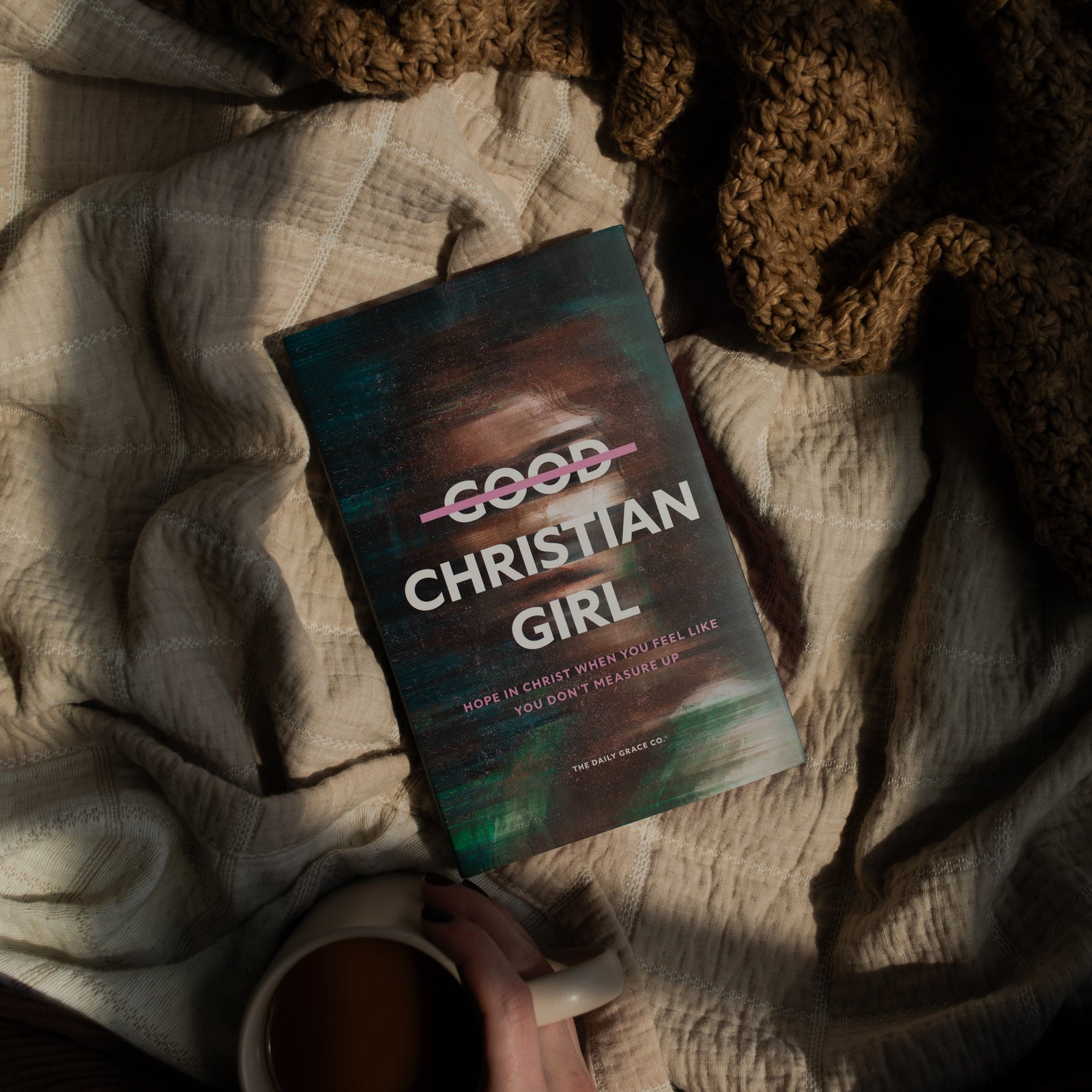 The Good Christian Girl book cover on a tan blanket near a coffee cup