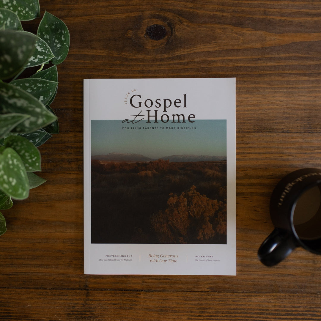 A white book on a wood table next to a black coffee cp and a plant