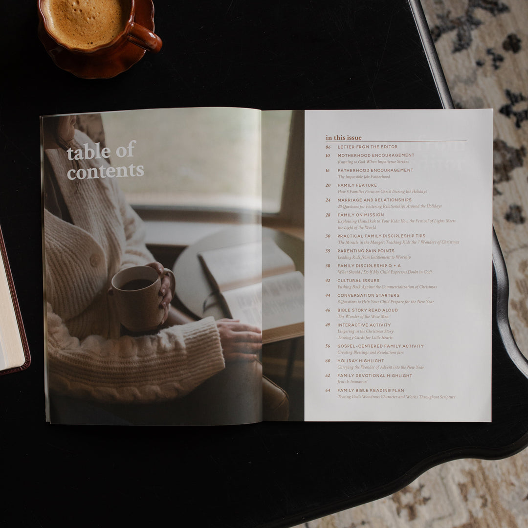 Gospel at Home Issue 10 opened to the table of contents page on a black table near a coffee cup