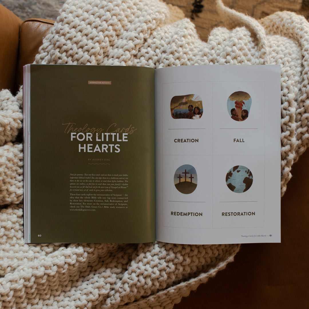 Gospel at Home Issue 11 opened to the theology cards for Little Hearts page on a white knitted blanket