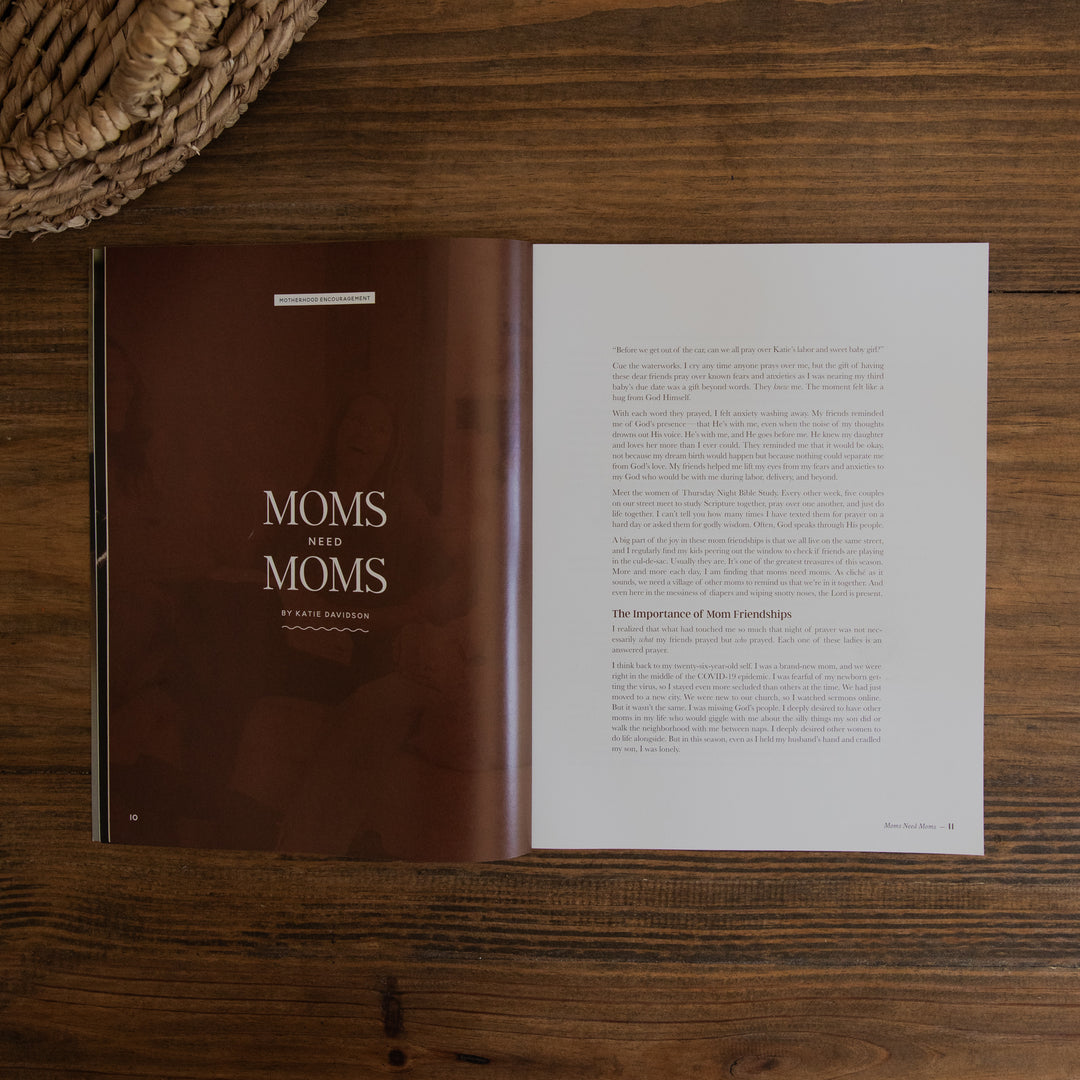 An open magazine page titled "Moms Who Moms" by Erica Richardson, featuring a dark brown cover on the left page and white text pages on the right, photographed flat on a dark wood tabletop with a woven basket edge visible in the top-left corner.