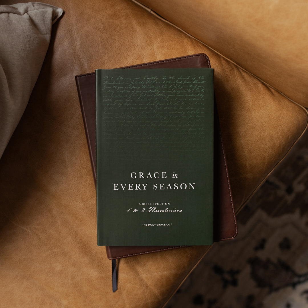 Green book titled 'Grace in Every Season' on a brown leather surface