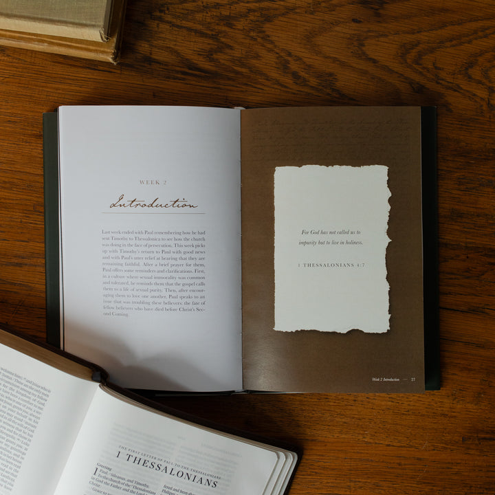 Open book on a wooden surface with a piece of paper attached to it.