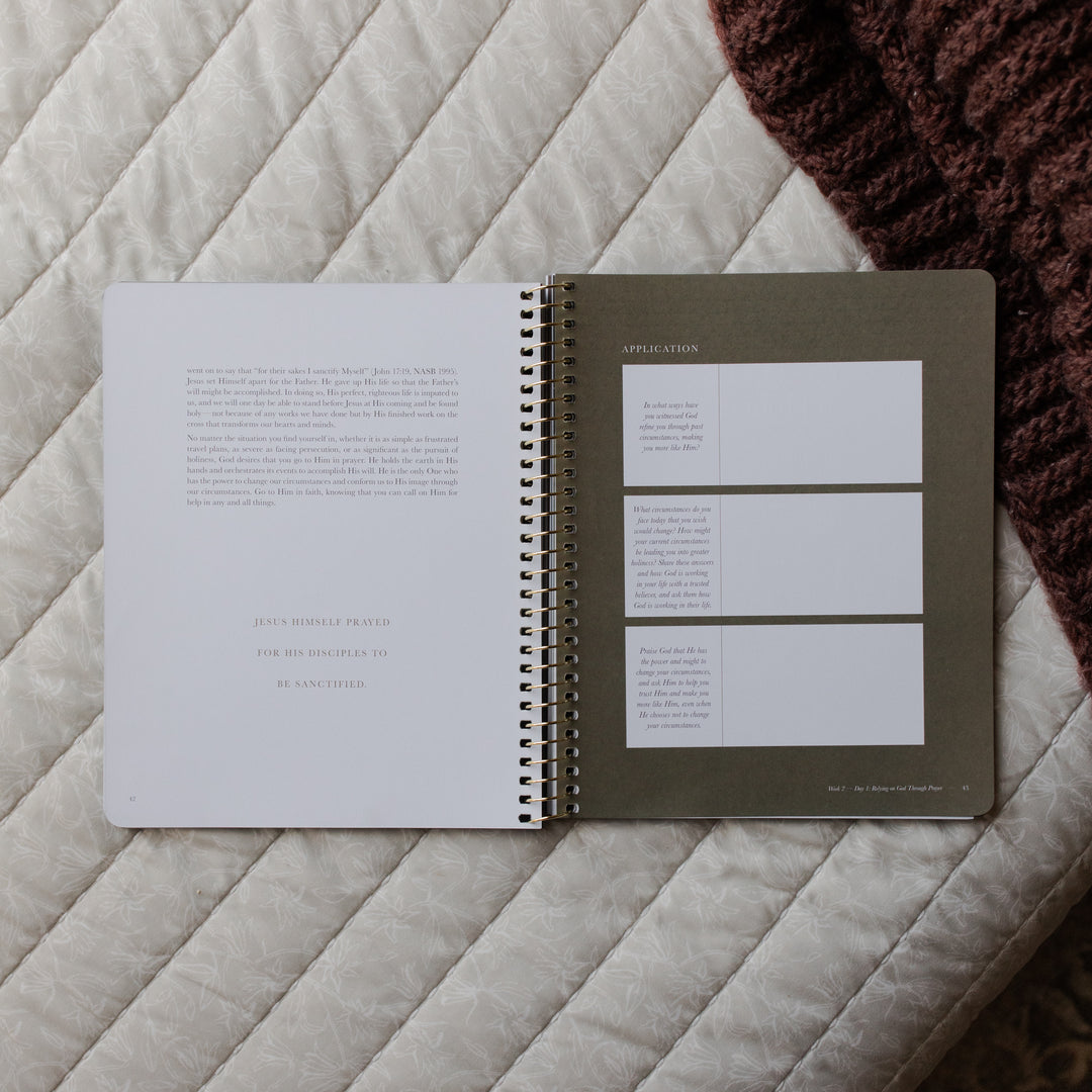 Open spiral-bound notebook on a textured surface with visible text and design elements.