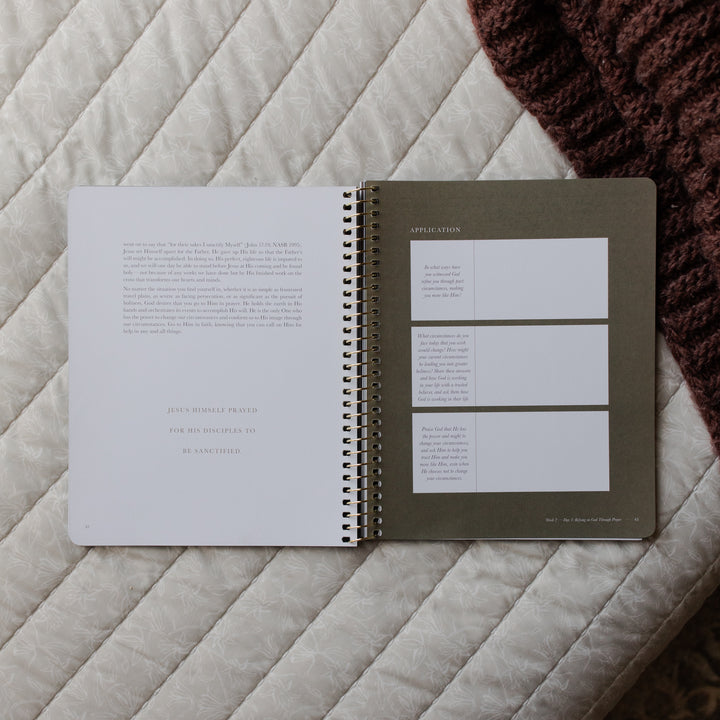 Open spiral-bound notebook on a textured surface with visible text and design elements.