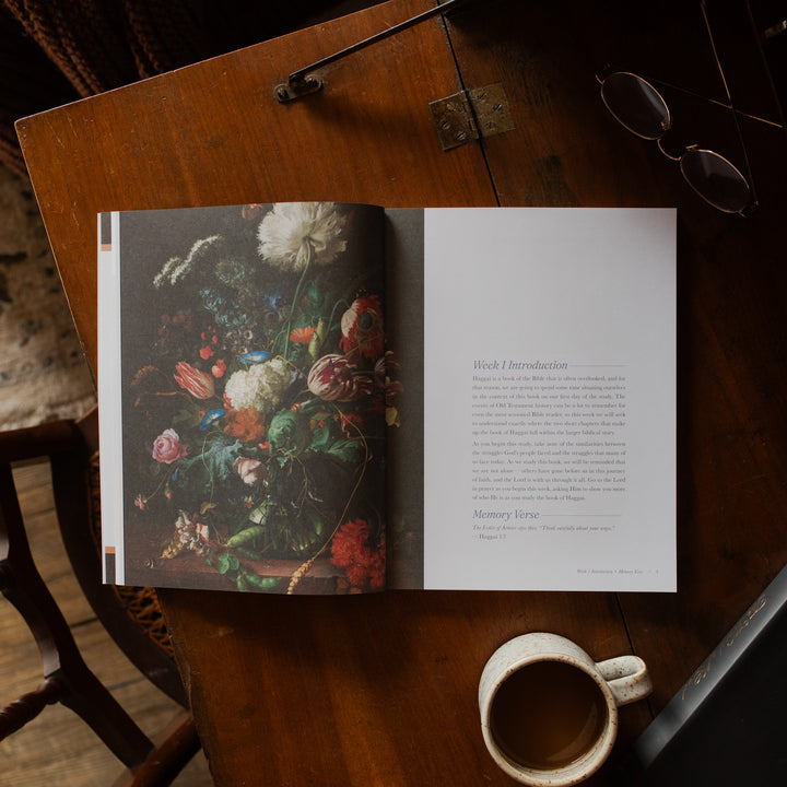 Haggai study opened to the week 1 introduction page on a wooden desk near a pair of eyeglasses