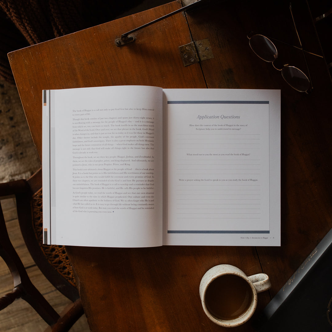 Haggai study opened to the applications page on a wooden desk near a pair of eyeglasses