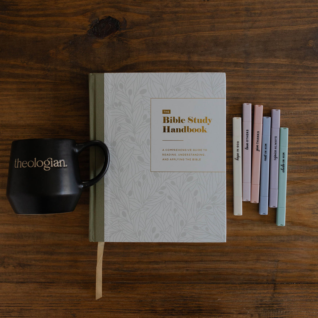 Theologian mug, The Bible Study Handbook and muted pastel highlighters on a table