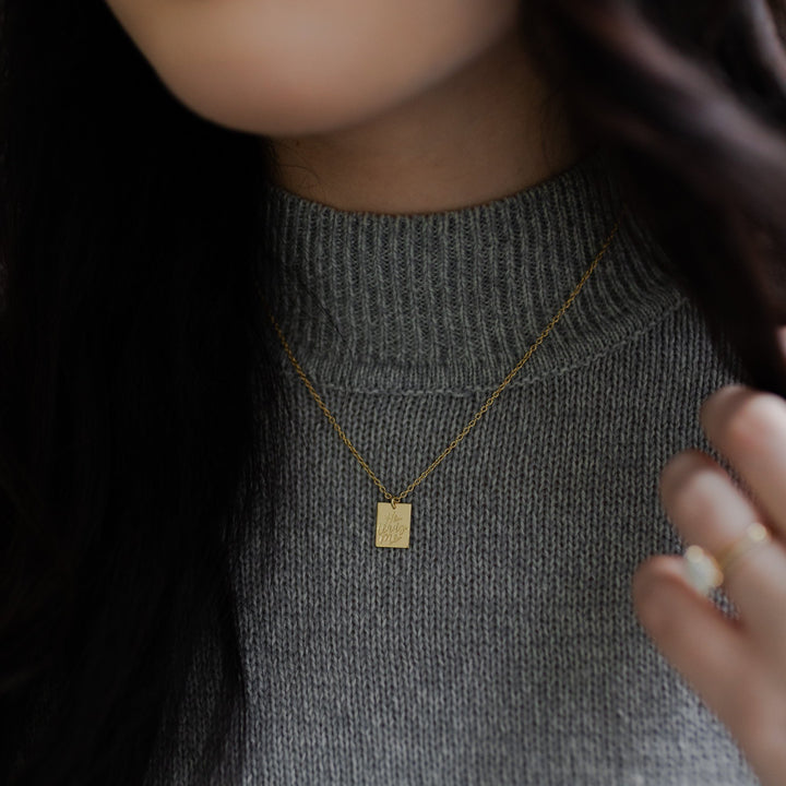 He Leads Me Necklace around woman's neck on a grey sweater