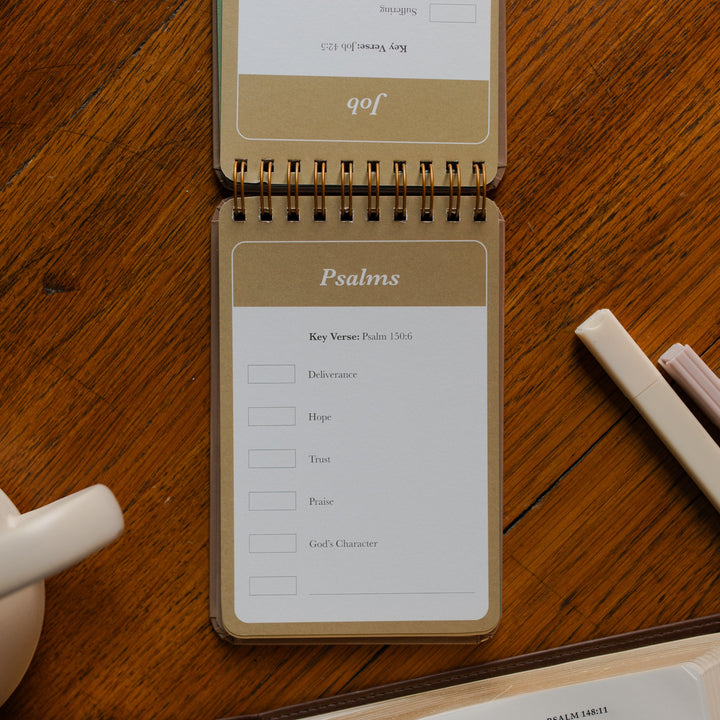 Highlighting through Scripture flipbook flipped to the Psalms Card near an open bible on a wooden table near some highlighters