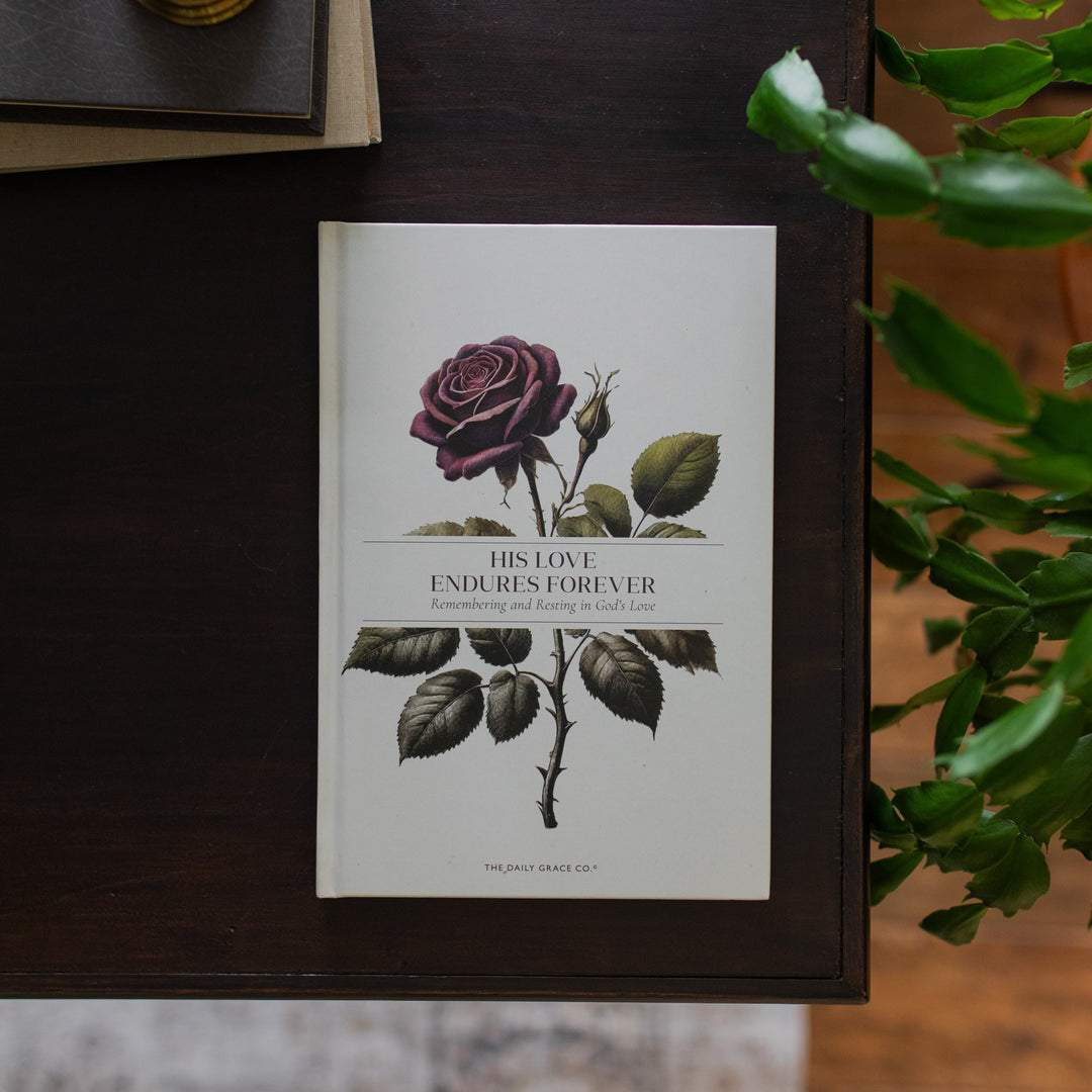 His Love Endures Forever book cover on a dark wooden table with some greenery nearby