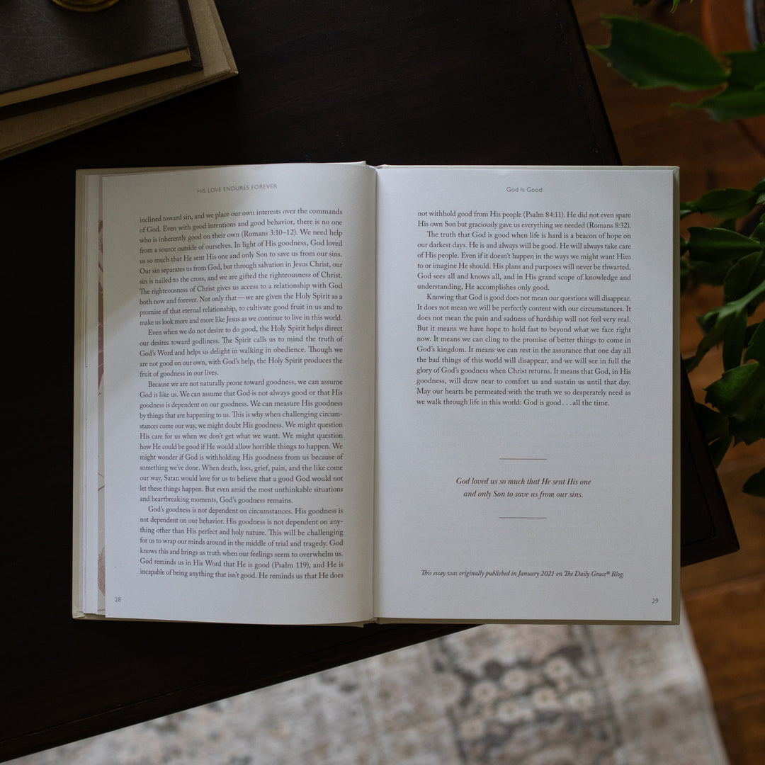 His Love Endures Forever book opened to the God is Good ending paragraph page on a dark wooden table with some greenery nearby
