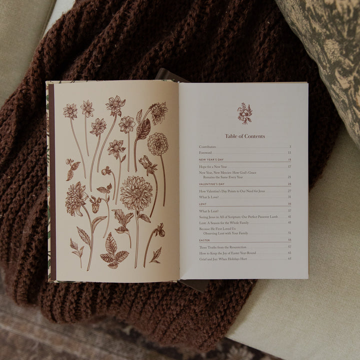 An open book laid flat on a brown knitted blanket, showing a floral illustration on the left page and a Table of Contents on the right page.