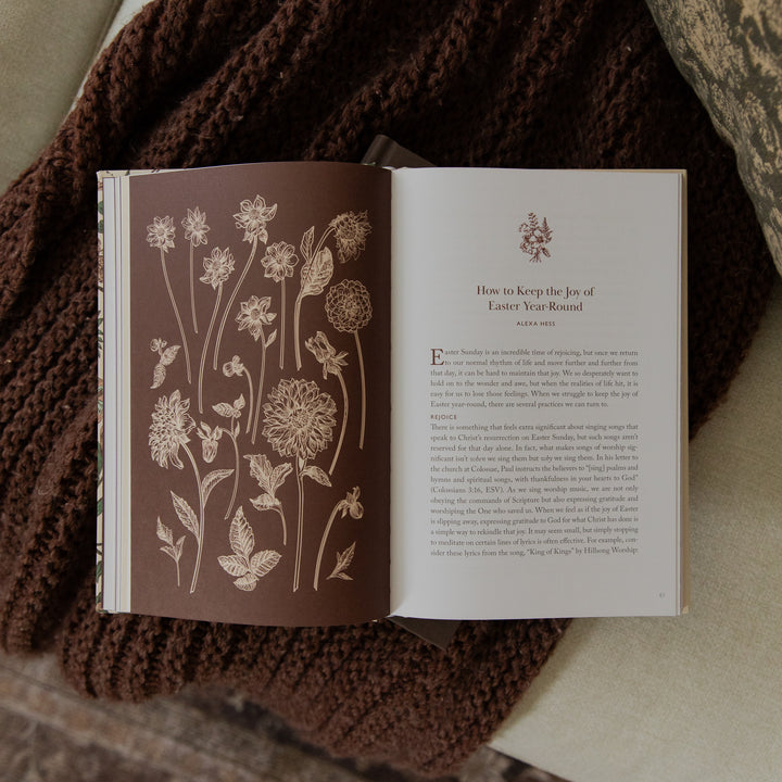An open book laid flat on a textured brown knit blanket, showing a floral illustration on the left page and a printed article titled 'How to Keep the Joy of Easter Year Round' on the right page.