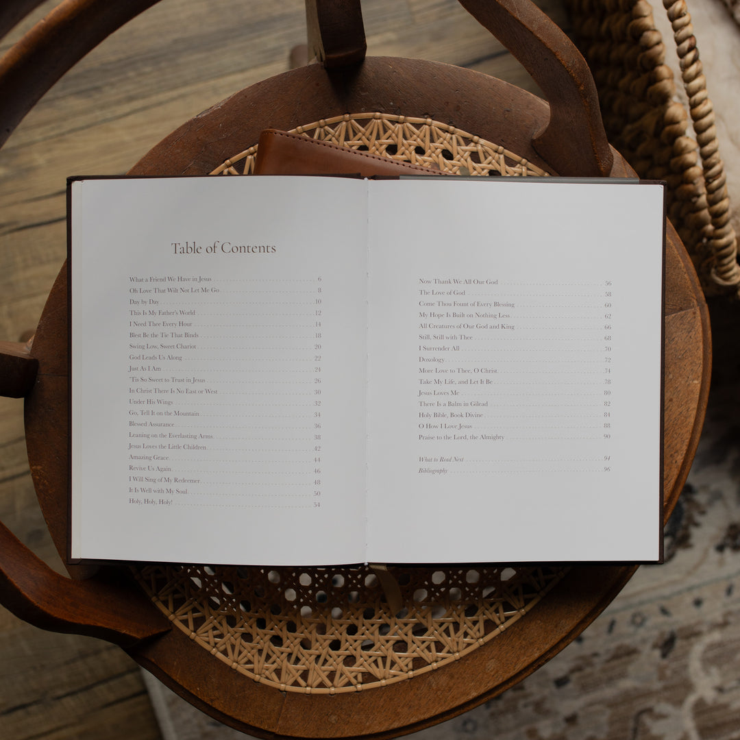 The I need Thee Every Hour book opened to the table of contents page on a wicker chair