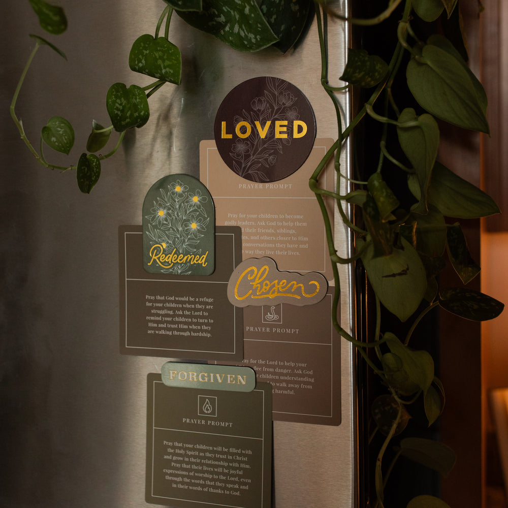 All of the Identity Magnets holding verse cards to a refrigerator near greenery